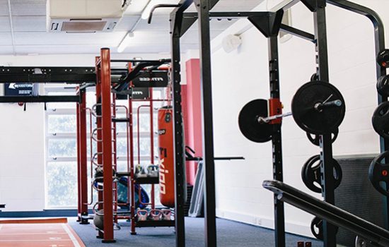A gym with a weight rack, barbells, and other equipment